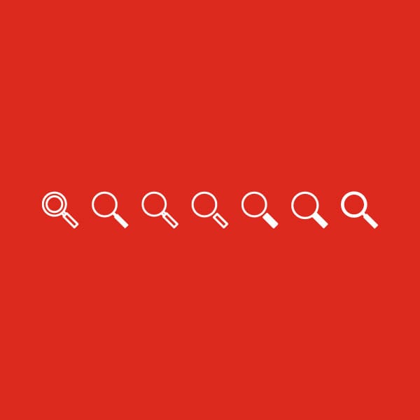 Various looks of white magnifying glass icons on Grainger red to determine the best icon design.